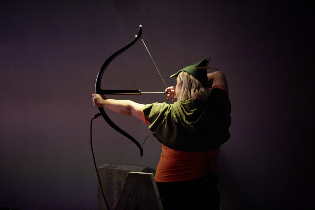 woman dressed as Robin Hood using a bow