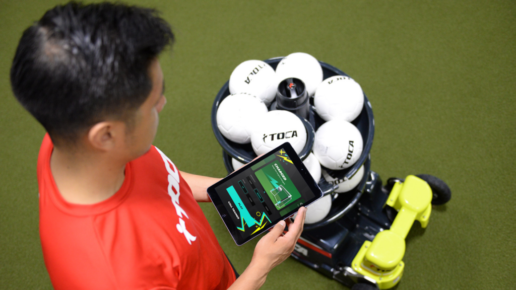 man using TOCA Sport next to a towers of footballs