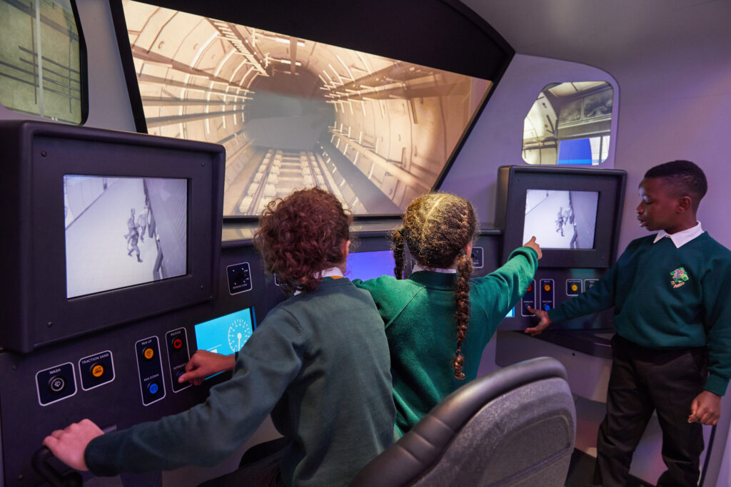 3 kids checking consoles in London Transport Museum